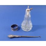 A silver button hook with floral and ribbon decoration, a silver collared cut glass atomiser and a