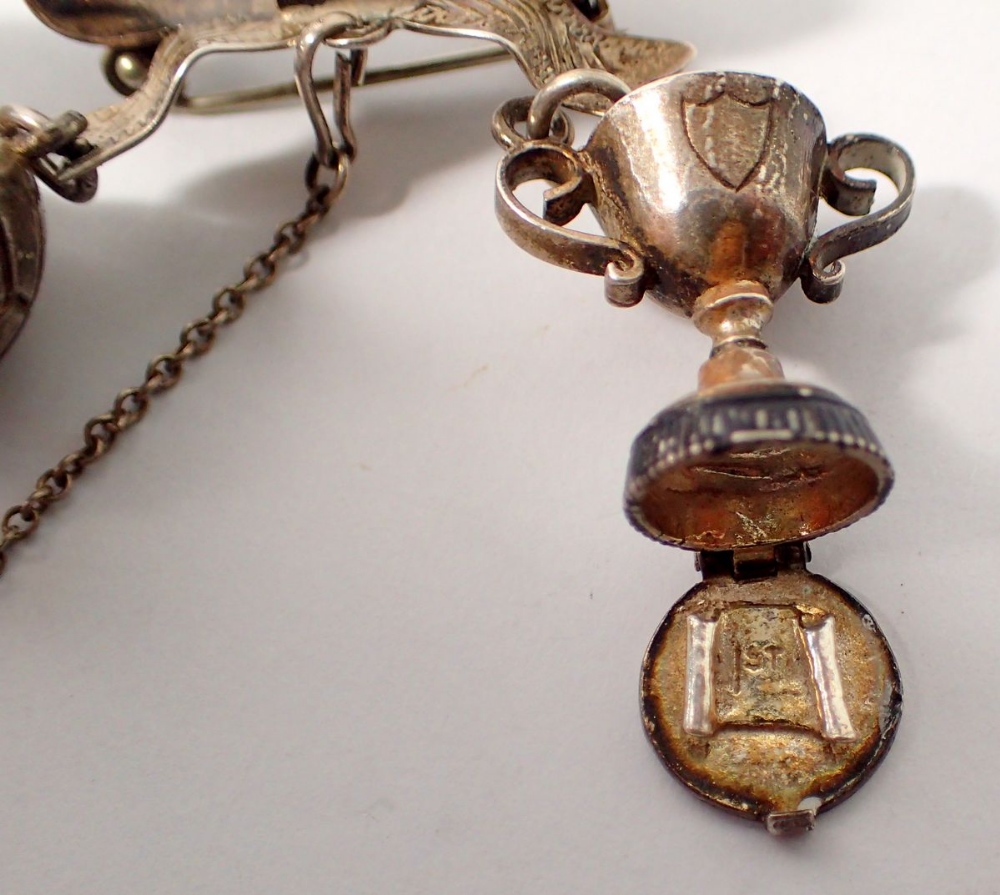 A silver ribbon form brooch suspended unusual football and trophy cup charms, 15g - Image 3 of 4