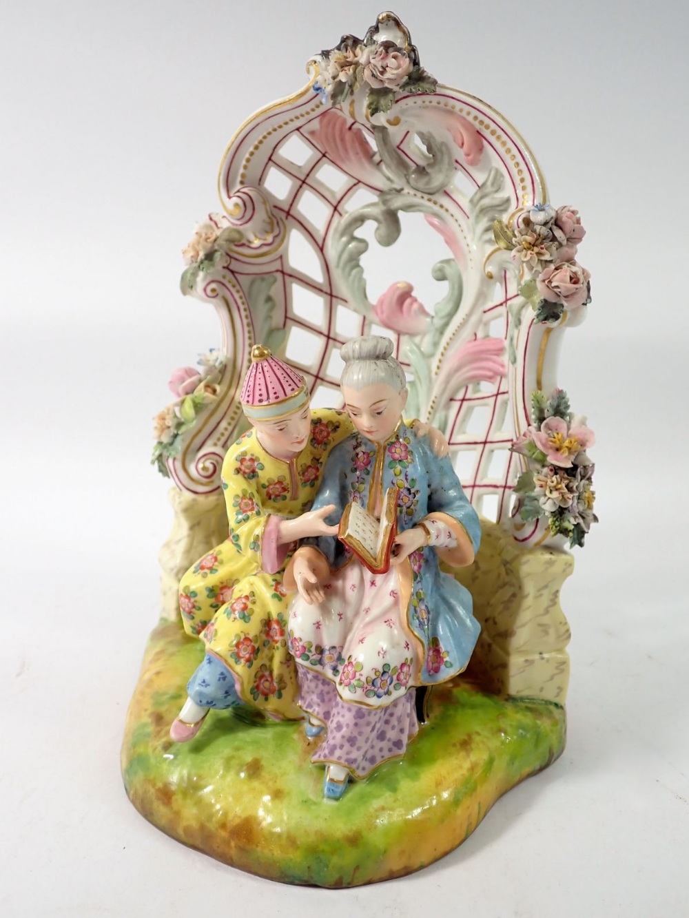 A 19th century Meissen style group of Chinese couple seated reading in floral and scrollwork