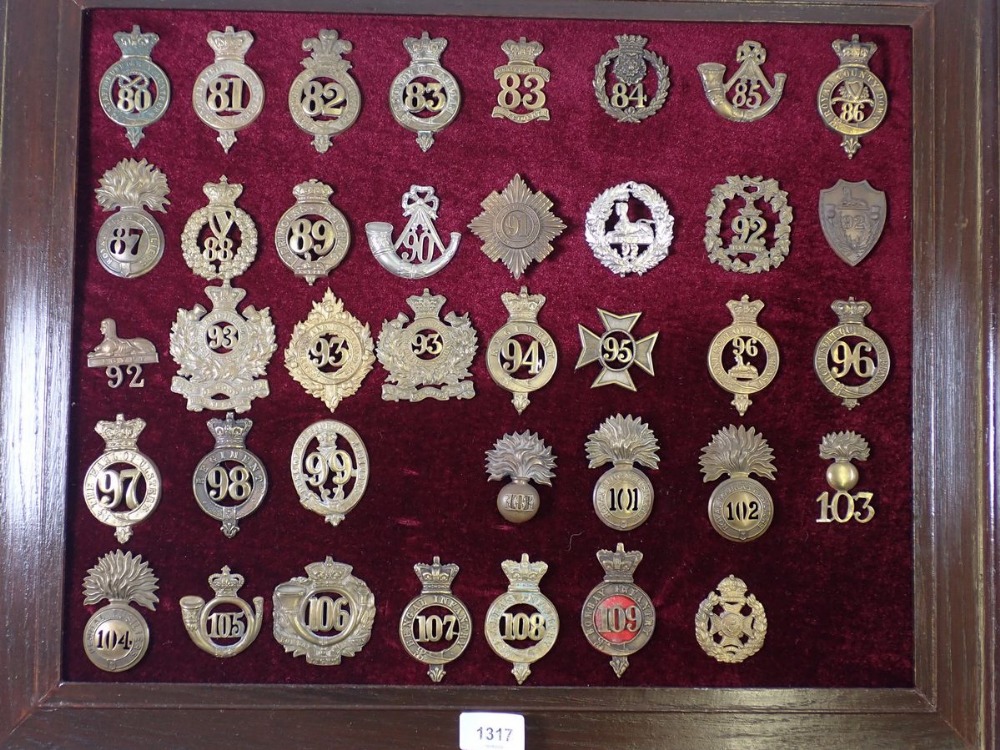 A framed display of thirty eight military cap badges