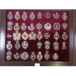 A framed display of thirty eight military cap badges