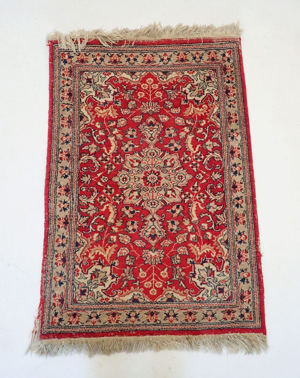 A small Persian style rug with floral medallion on red ground, 96 x 66cm