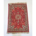 A small Persian style rug with floral medallion on red ground, 96 x 66cm