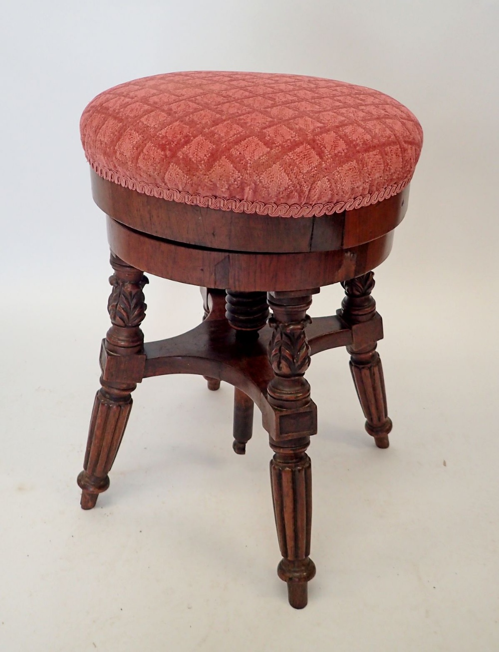 A Victorian mahogany revolving piano stool on reeded supports