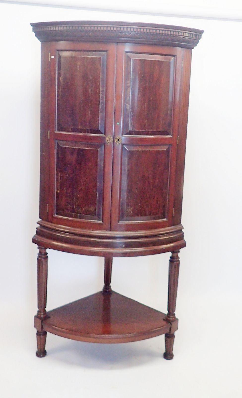 A 19th century bow fronted mahogany corner cabinet with unusual hinged secret compartment to