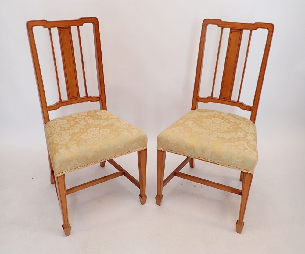 A pair of Edwardian satinwood slat back chairs on square tapered supports with spade feet