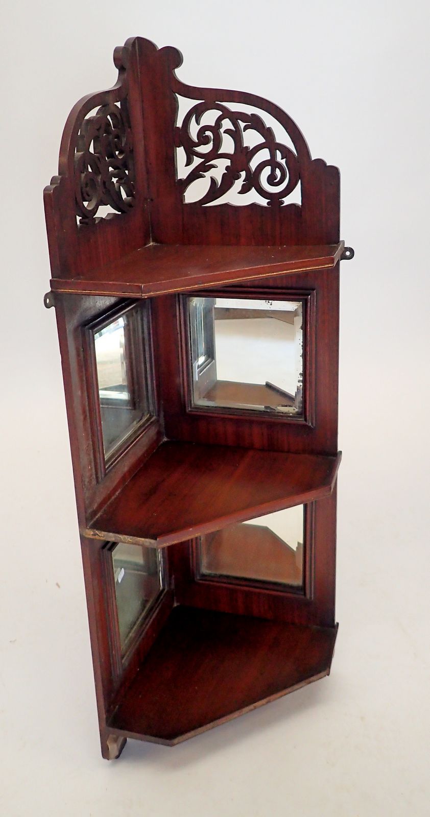 An Edwardian mahogany set of mirrored corner shelves with decorated pierced surmount, 80cm tall