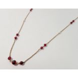 A 9 carat gold chain interspersed with garnets and seed pearls, 8.5g, 76cm long