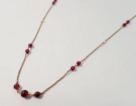 A 9 carat gold chain interspersed with garnets and seed pearls, 8.5g, 76cm long