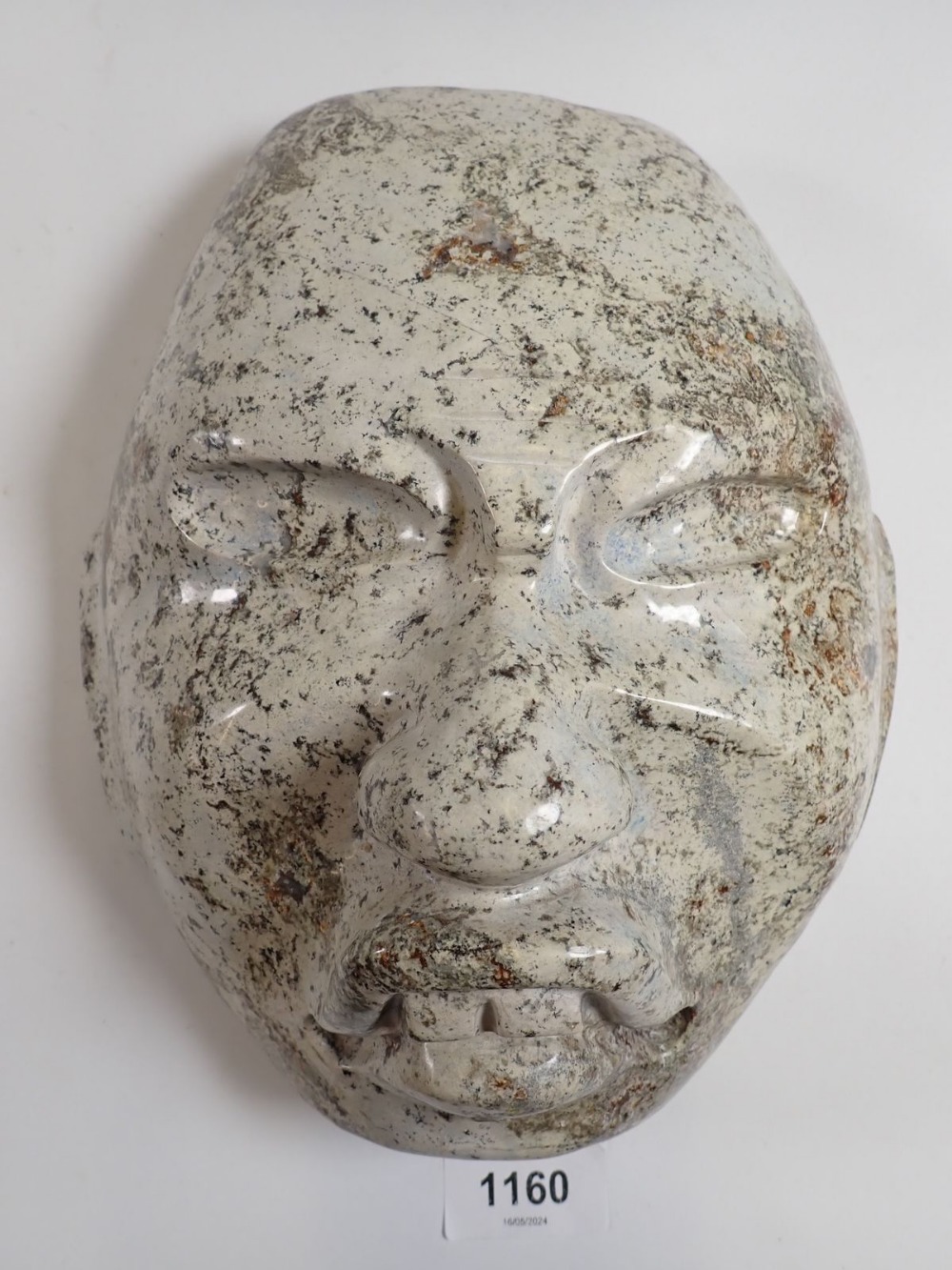 A pale stone carving of a face mask in Olmec style, 23 x 20cm