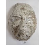 A pale stone carving of a face mask in Olmec style, 23 x 20cm