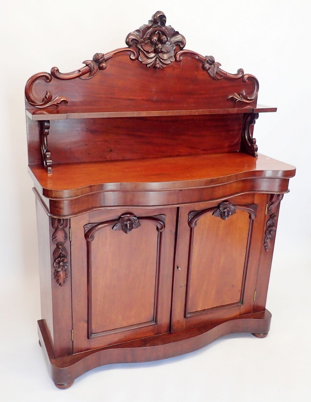 A Victorian mahogany chiffonier with shelf back over serpentine front, the two panelled cupboards