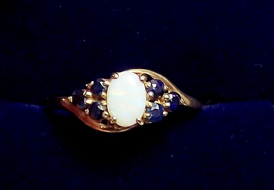 A 9 carat gold ring set opal flanked by six sapphires, size M, 1.1g