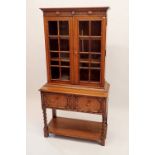 An early 20th century bookcase of very small proportions with two glazed doors over drawer all