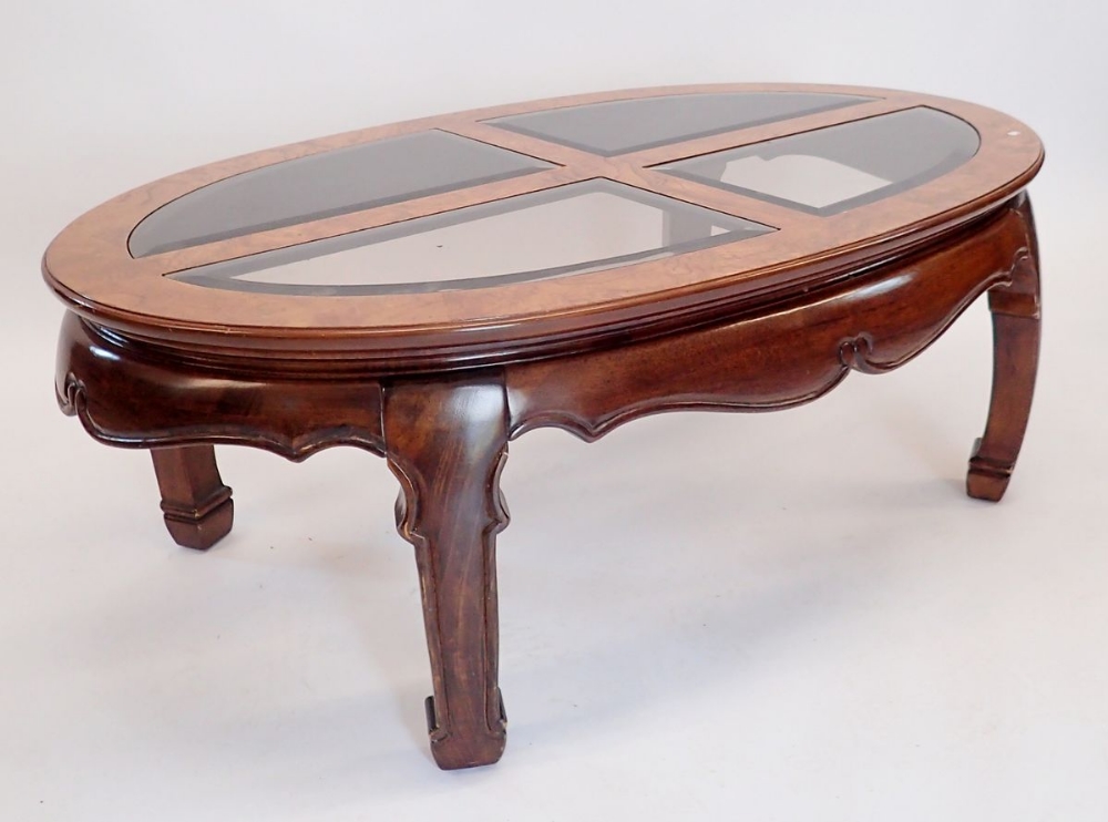 A Waring & Gillows oriental style oval coffee table with inset glass panels to top, 122 x 74 x 44cm