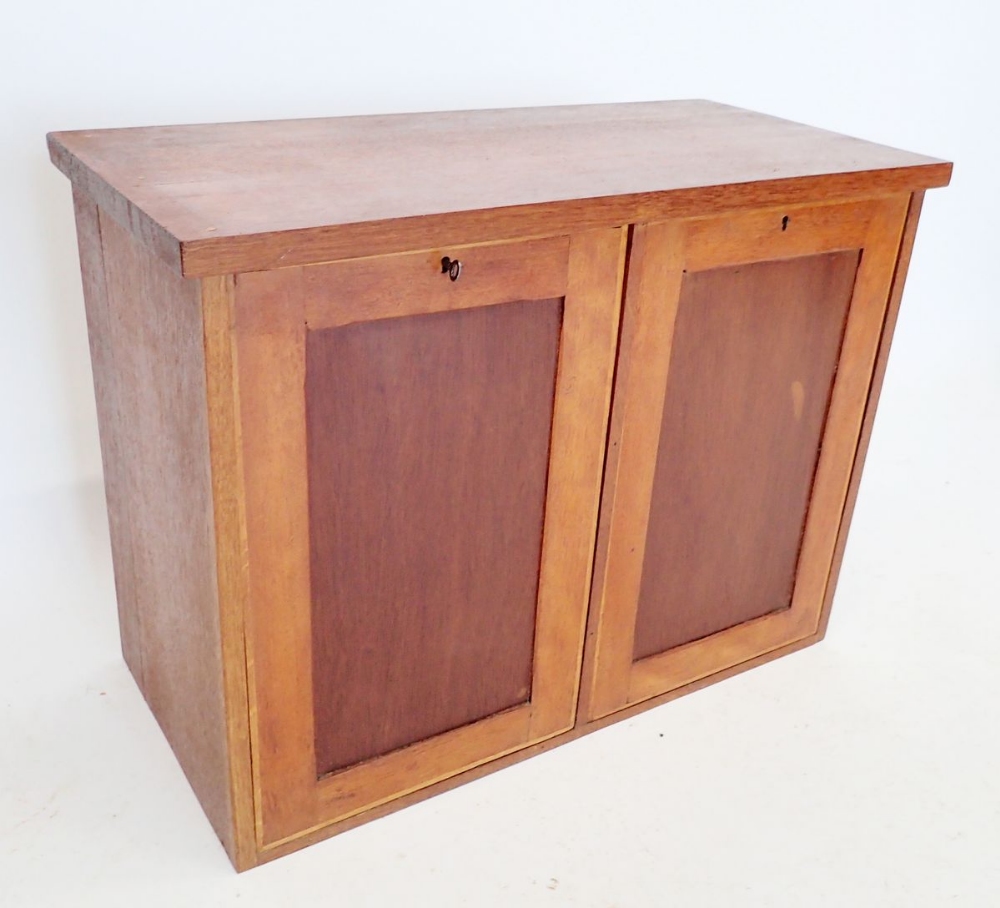 A teak hand made collectors cabinet enclosing drawers behind two locking panels, some drawers