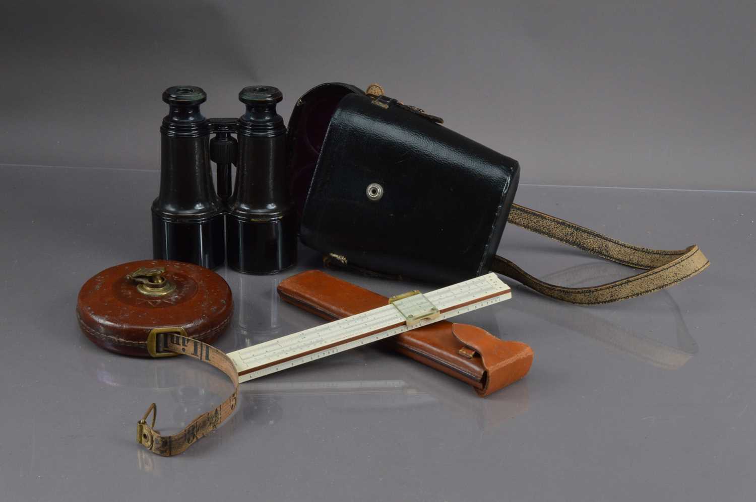 A pair of binoculars and a surveyor's tape measure and a slide rule,