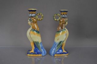 A pair of faience or majolica neoclassical harpy form candlesticks,