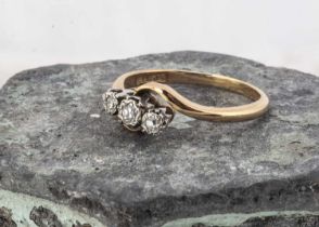 An 18ct gold and platinum set three stone cross over ring,