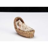 A miniature Grodnerthal dolls’ house doll in cradle,