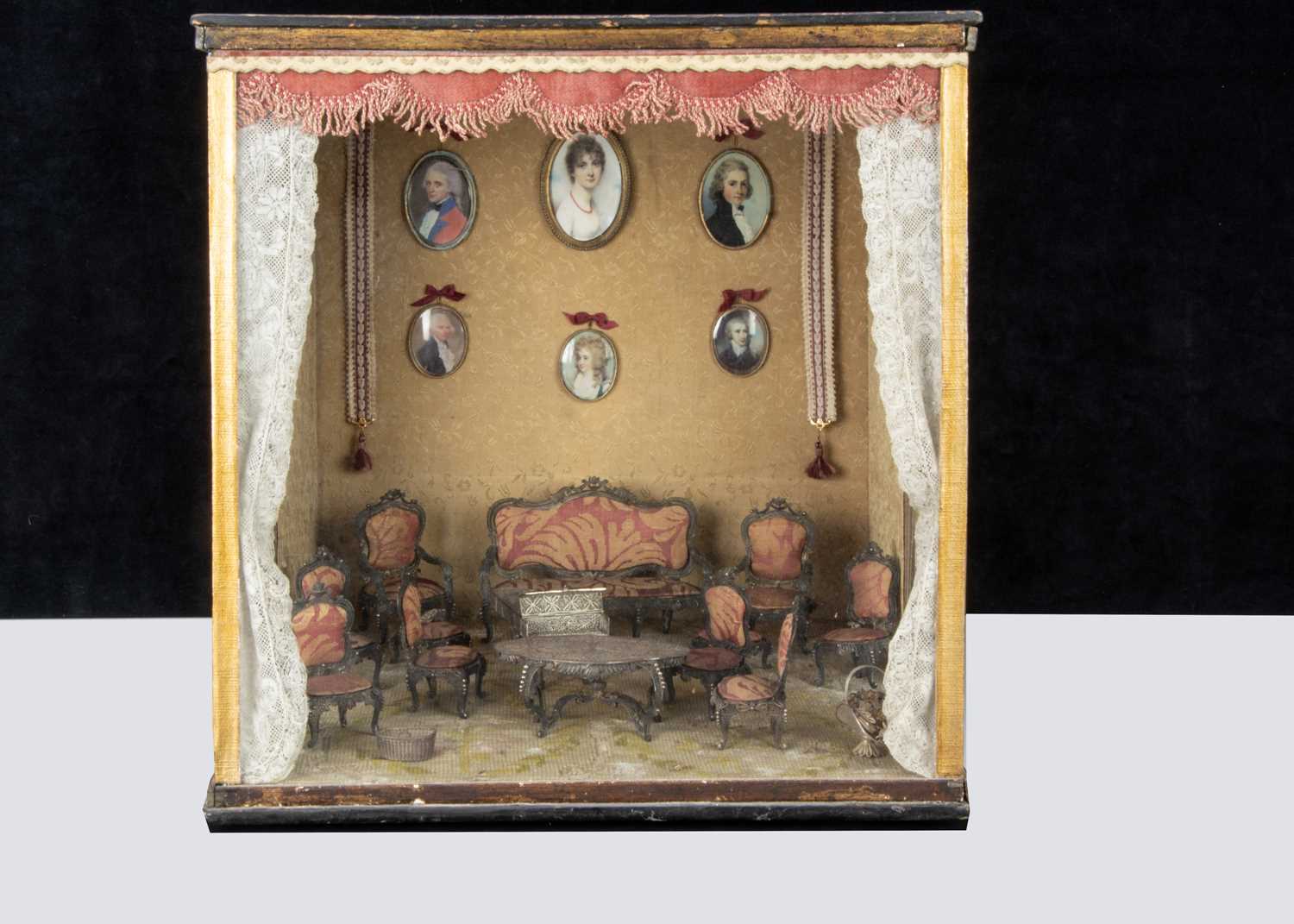 A room setting display case with ‘silver’ white metal filigree dolls’ house furniture,