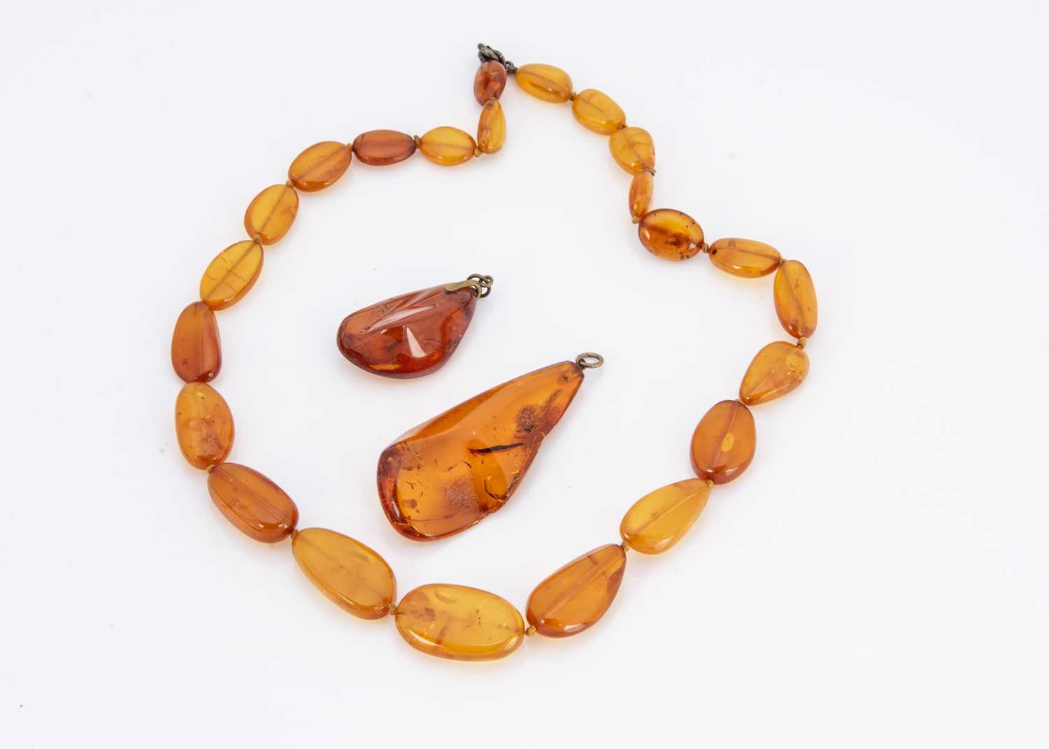 Two Baltic amber pendants both having insect inclusions,