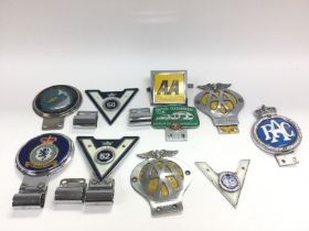 A collection of various vintage car badges includi