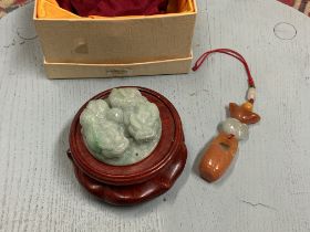 A modern Chinese green jade carved amulet on wooden stand together with a hardstone key ring