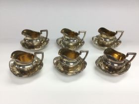 A set of 6 silver miniature jugs and saucers marke