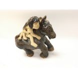 A Studio pottery horse with two people riding .