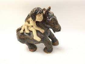 A Studio pottery horse with two people riding .