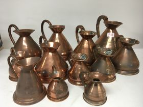 A collection of copper measuring jugs of graduatin