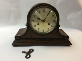 An oak metal clock with a silver dial and Arabic numerals.