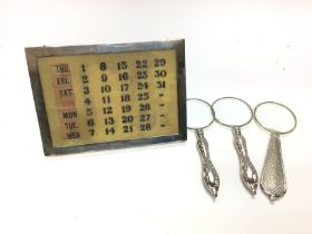 A silver calendar with three small magnifying glas