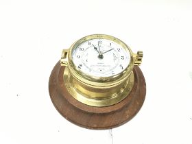 A brass time and tide clock mounted on wood base. Seen running. Postage B