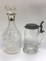 A wine decanter with a silver collar and an etched