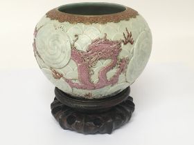 An unusual raised relief Chinese pot on a hardwood