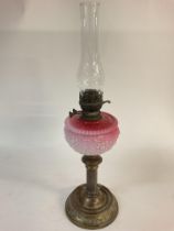 A Victorian pink glass oil lamp. 66cm tall. Postag