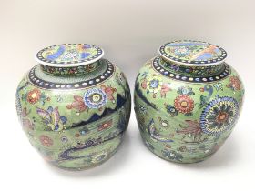 A pair of Chinese ginger jars with covers, decorated with flowers, butterflies on a green ground.