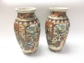 A pair of Japanese satsuma vases decorated with figures and landscapes. 30cm x 15cm.