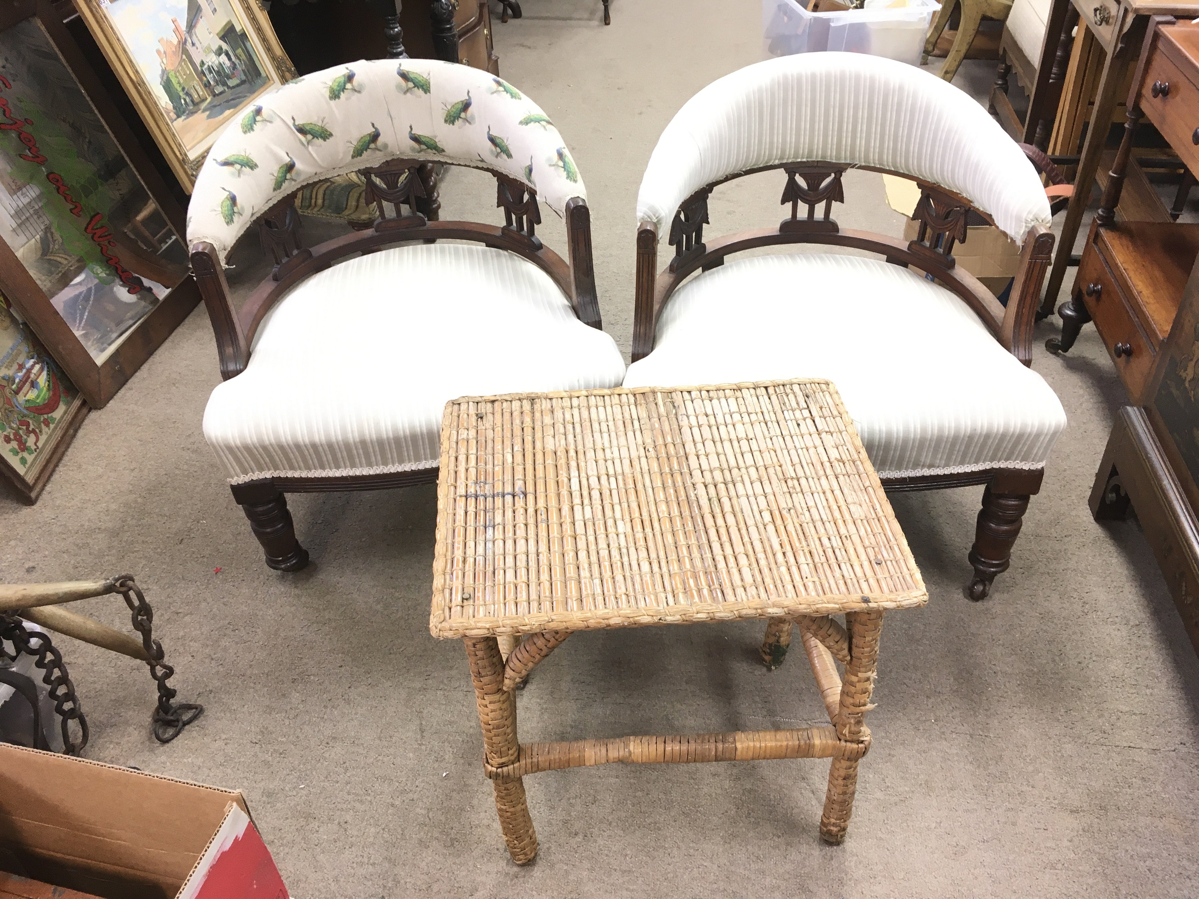 A pair of Edwardian tub chairs on caster feet, (66cm tall) and a small wicker/ bamboo table