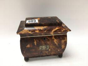 A tortoiseshell tea caddy with hinge lid enclosing 2 compartments. On brass circler feet. 15cm x