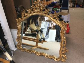 An elaborately carved gilt framed overmantel mirro