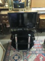 A small flat screen tv Approx 56cm, with a dvd player and modern chrome and glass tables.