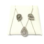 A silver pendant and earring set with white stones