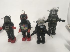 A collection of four toy robots. Two are tin plate