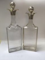 Two glass decanters with silver collars .