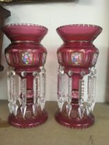 A pair of Victorian style cranberry lustres with floral panels and glass drops 33 cm .