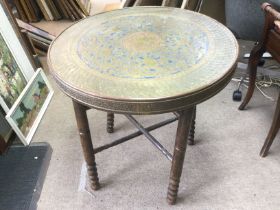 A Middle Eastern brass topped folding table, approx diameter 60cm. Shipping category D.