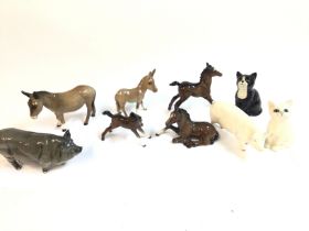 A collection of Beswick donkeys foals pigs cats and one Royal Doulton cat. Postage D